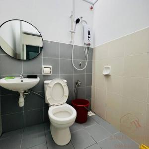 a bathroom with a toilet and a sink and a mirror at Jalan Sena Indahpura Landed House in Kulai