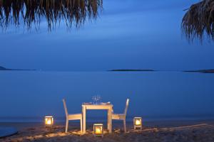 a table and chairs on the beach at night at Contaratos Beach Hotel in Naousa