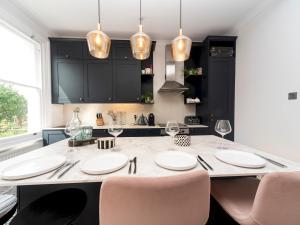 a kitchen with a large table with chairs and lights at Pass the Keys Cosy and Chic Flat Near Greenwich Park in London
