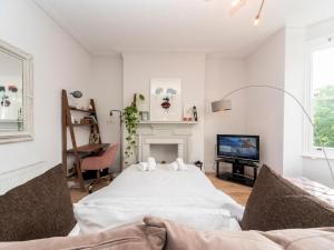 una camera bianca con letto e TV di Pass the Keys Cosy and Chic Flat Near Greenwich Park a Londra