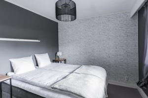 a bedroom with a white bed and a brick wall at Arctic Holiday Apartments 3 in Rovaniemi