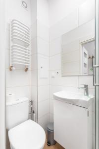 a white bathroom with a toilet and a sink at Szymanowskiego 4 by Homeprime in Warsaw