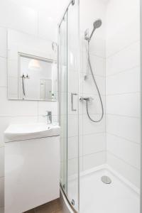 a white bathroom with a shower and a sink at Szymanowskiego 4 by Homeprime in Warsaw