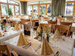 un restaurante con mesas y sillas blancas y ventanas en Alpen Glück Hotel Kirchberger Hof, en Kirchberg in Tirol