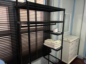 a black shelf with towels on it in a bathroom at ThaiTae GuestHouse HuaHin in Hua Hin