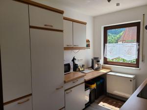 a small kitchen with white cabinets and a window at Ferienwohnung am Südhang in Gernsbach