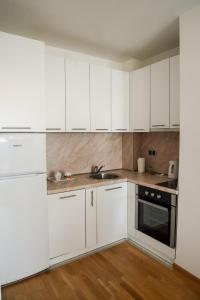 a white kitchen with white cabinets and a sink at Apartman “Ada” in Sarajevo