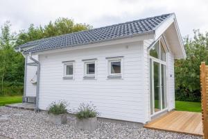 une petite maison blanche avec un toit mansardé dans l'établissement Malevik Tiny House, à Kullavik