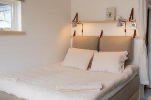 a bedroom with a bed with white sheets and pillows at Malevik Tiny House by the Coast in Kullavik
