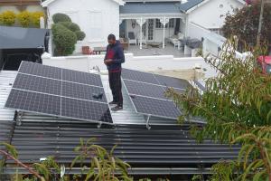 ケープタウンにあるRosedene Lodge - 24h solar with pool and gardenの家屋の太陽電池パネルの上に立つ男