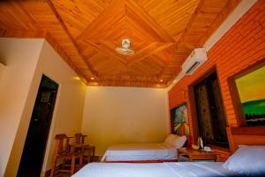 1 dormitorio con 2 camas y techo de madera en Sườn Đồi Bungalow Homestay, en Phong Nha