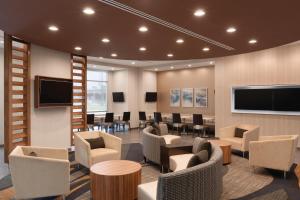 a waiting room with chairs and tables and a tv at SpringHill Suites by Marriott Houston Northwest in Houston