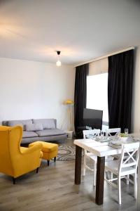 a living room with a table and yellow chairs at Nordica central apartment in Rovaniemi