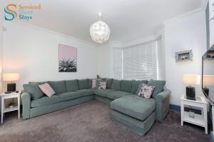 ein Wohnzimmer mit einem grünen Sofa und Stühlen in der Unterkunft Light and spacious three bedroom house in Margate close to beach and amenities in Margate