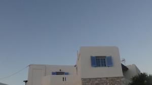 un edificio bianco con una finestra blu sopra di Summer dream ad Aliki