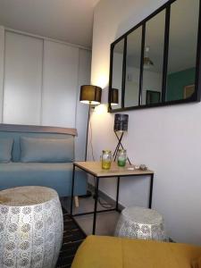 een woonkamer met een tafel, een bank en een spiegel bij Très bel F2 avec pleine vue mer. in Langrune-sur-Mer