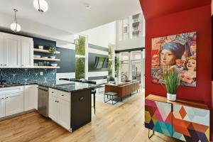 a kitchen with white cabinets and a red wall at Iridescence Center Midtown Piedmont Park King Bed Loft in Atlanta