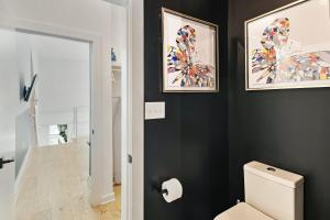 a bathroom with a toilet and two pictures on the wall at Iridescence Center Midtown Piedmont Park King Bed Loft in Atlanta