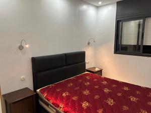 Un dormitorio con una cama con sábanas rojas y una ventana en Centre d estivage, en Moulay Bousselham