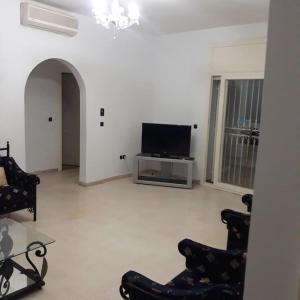 a living room with a flat screen tv and chairs at Appartement bord de mer à Nabeul in Nabeul