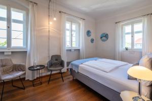 a bedroom with a bed and two chairs and windows at Villa Sommerach in Sommerach