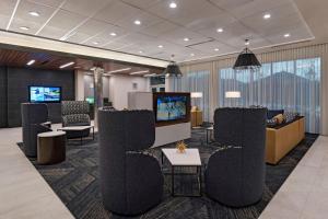 a lobby with chairs and a tv in a building at Courtyard by Marriott Houston Sugar Land/Lake Pointe in Sugar Land