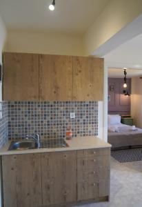 uma cozinha com armários de madeira, um lavatório e uma cama em Το Μπαλκόνι Του Όρλιακα 