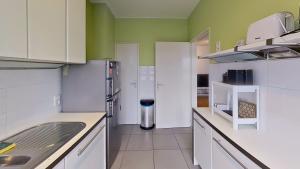 uma cozinha com armários brancos e paredes verdes em nice and cosy apartment em Edegem