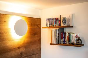 een plank met een spiegel en boeken aan een muur bij La Rosa delle Alpi Luxury Apartment in Chamois