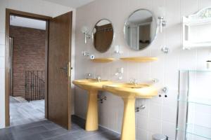 a bathroom with two sinks and two mirrors at Holländer Flair Friedrichstadt in Friedrichstadt