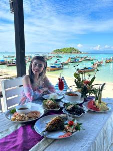 a woman sitting at a table with plates of food at Lipe Power Beach Resort in Ko Lipe