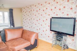 a living room with a couch and a flat screen tv at Immaculate 3-Bed House in Dudley in Dudley