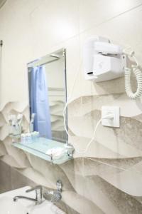 a mirror on a wall above a sink in a bathroom at Aperol Hotel in Tashkent +49 photos
