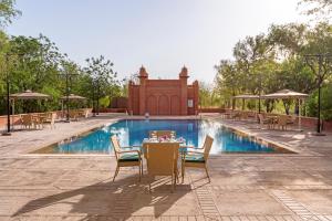 a table and chairs in front of a swimming pool at Gaj Kesri by 7Apple Resorts in Bikaner