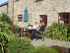 a man and woman sitting at a table with an umbrella at Wheal Kitty nr Truro in Truro