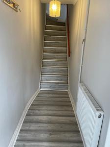 a staircase in a room with white walls and wooden floors at Luxury 2 bedroom maisonette with private garden, fibre WIFI, Sky channels in Camberley