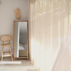 a mirror in a room with a bed and a chair at Acacia - Explore your senses in Preveza