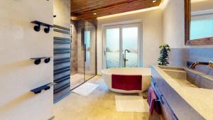 a bathroom with a tub and a glass shower at PitzPlus Appartements in Sankt Leonhard im Pitztal