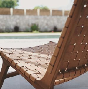 a wooden chair sitting in front of a pool at Acacia - Explore your senses in Preveza