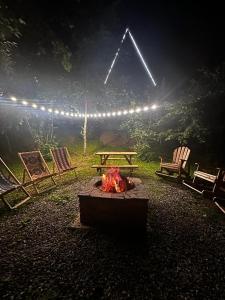 a fire pit with chairs and a picnic table and lights at GreenWood Cottages Merisi in Merisi