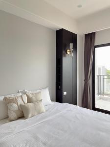 a white bedroom with a large bed and a window at Muzhu B&B in Yilan City