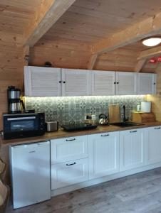 a kitchen with white cabinets and a wooden ceiling at morska chata in Lubiatowo