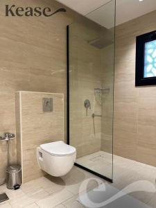 a bathroom with a toilet and a glass shower at Kease Malqa B-4 Royal Touch AZ31 in Riyadh