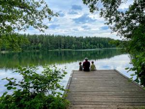Un uomo e due bambini seduti su un molo sul lago di Marzenie Dziadka - siedlisko obok Augustowa 