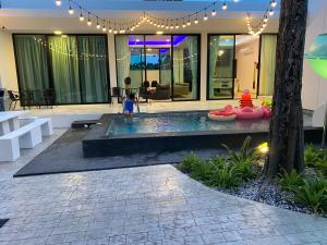 a child standing in front of a house with a fountain at 168 Garden Pool Villa in Nong Prue