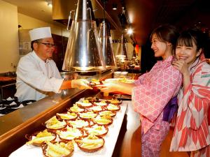 a man and two women standing in a kitchen preparing food at Ooedo Onsen Monogatari Minoh Kanko Hotel in Minoo