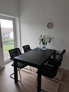 a black dining room table with chairs and a vase of flowers at Zimmer Nähe Darmstadt in Roßdorf