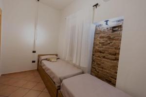 een kamer met 2 bedden en een bakstenen muur bij Zara House Holiday Home in Palmi