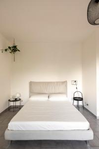 a white bed in a white room with two tables at Spazio Ancora appartamento a 500 m. dal mare in Rimini