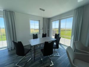 Un comedor con mesa y sillas y ventanas. en Ferienhaus "Rugard" in Dranske, en Dranske